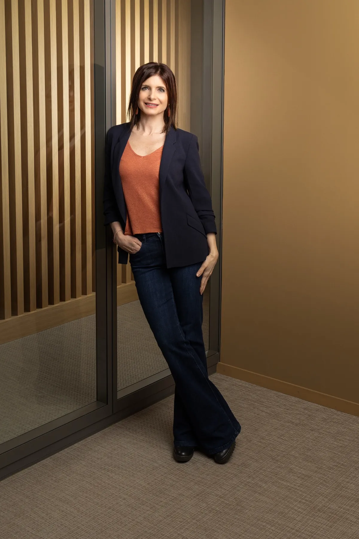Véronique Pagano, portrait en buste, dans un intérieur aux lignes architecturales de bois et de métal.